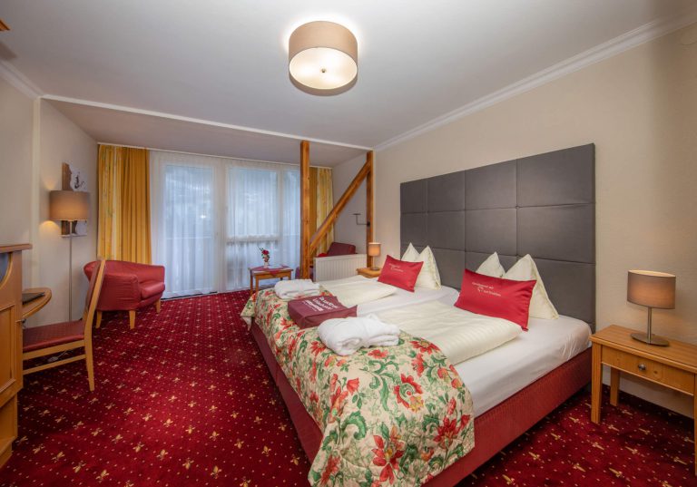 Gemütliches Zimmer im Vötter's Hotel mit Balkon, Roten Teppich und modernen Annehmlichkeiten.