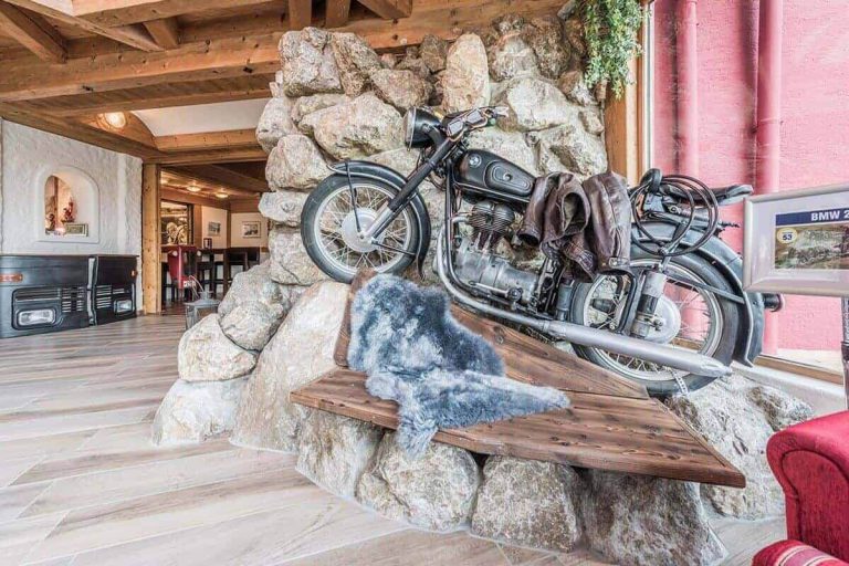 Historisches Motorrad auf Steinmauer im Vötter's Hotel, gemütliche Atmosphäre im Empfangsbereich.