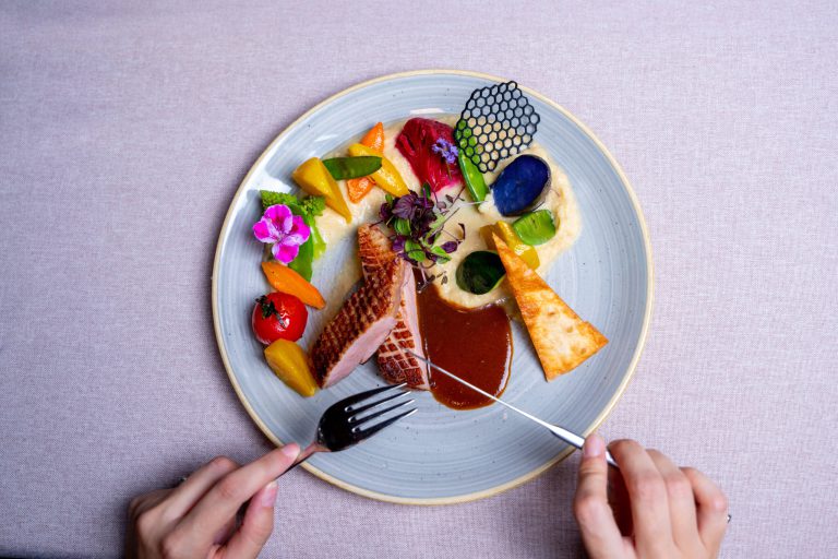 Köstliches Gourmetgericht mit Gemüse, Sauce und essbaren Blüten im Vötter's Hotel.