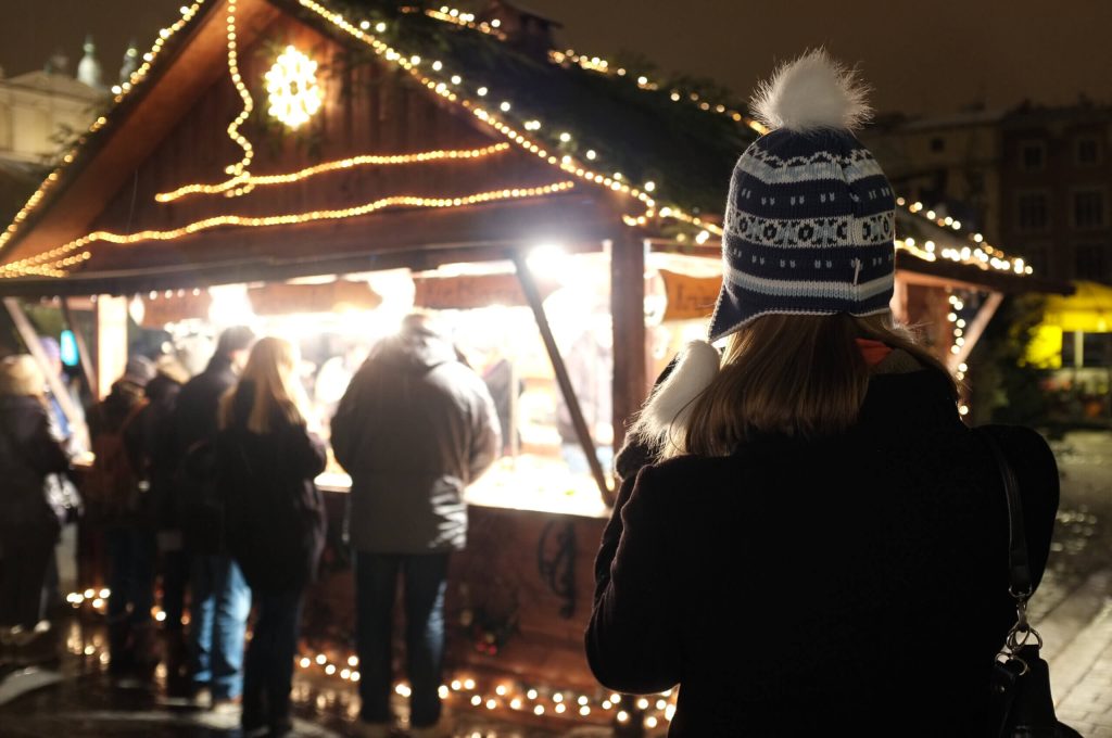 Beleuchteter Weihnachtsmarkt mit Besuchern an einem Stand in der Nacht.